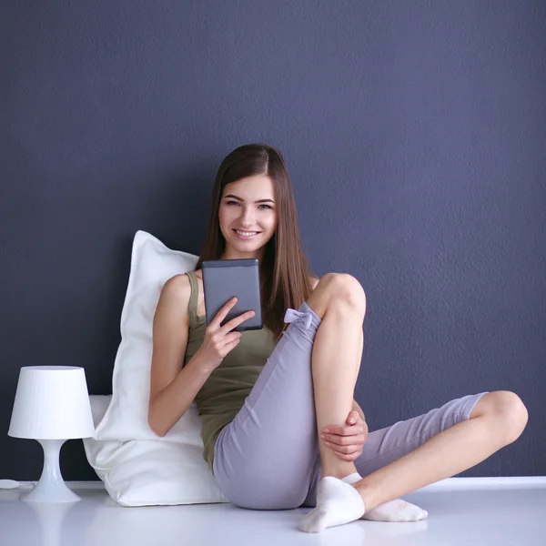 Pretty brunette woman sitting on the floor with a pillow and plane table
