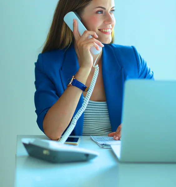 Portrait of a young woman on phone in front of a laptop computer