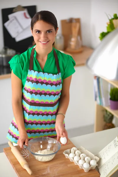 Smiling young woman in the kitchen, isolated on background