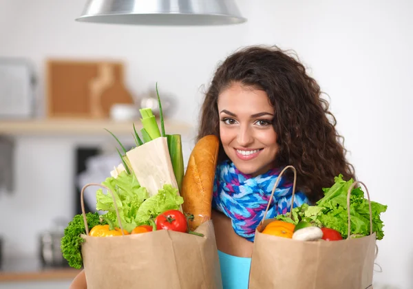 Young woman holding grocery shopping bag with vegetables Standing in the kitchen.