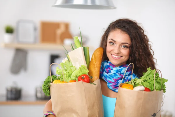 Young woman holding grocery shopping bag with vegetables Standing in the kitchen.