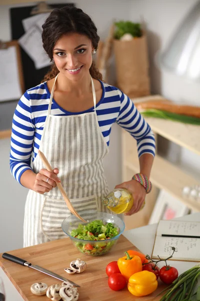 Smiling young woman  mixing fresh salad