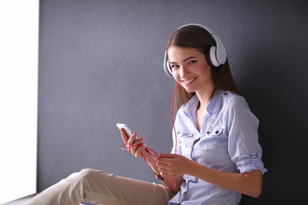 Smiling girl with headphones sitting on the floor