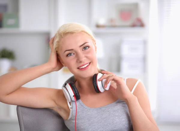 Young beautiful woman at home sitting on sofa and listening music