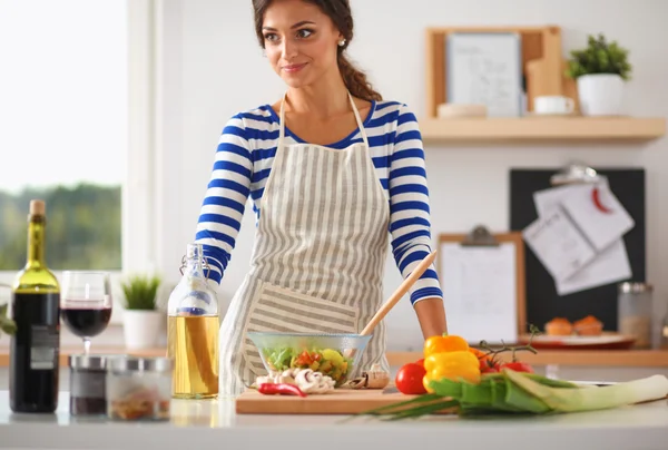 Smiling woman preparing salad in the kitchen
