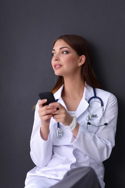 Young woman doctor sitting on the floor with your phone