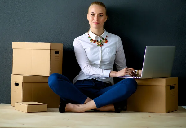 Woman sitting on the floor near a boxes  with laptop