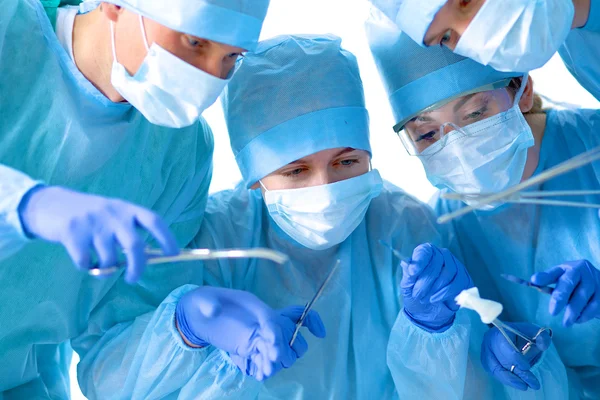 Below view of surgeons holding medical instruments in hands