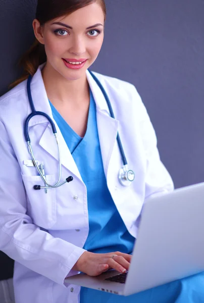 Female doctor working sitting on gray background