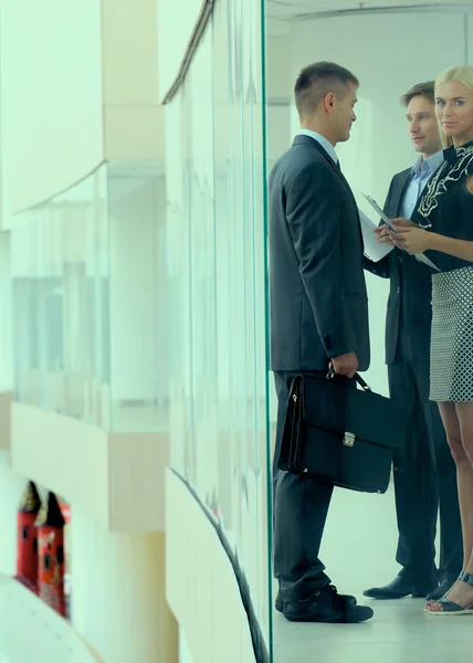 Business woman standing with her staff in background at modern office