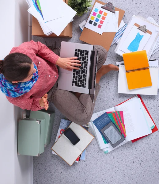 Student with books spread around working on a laptop