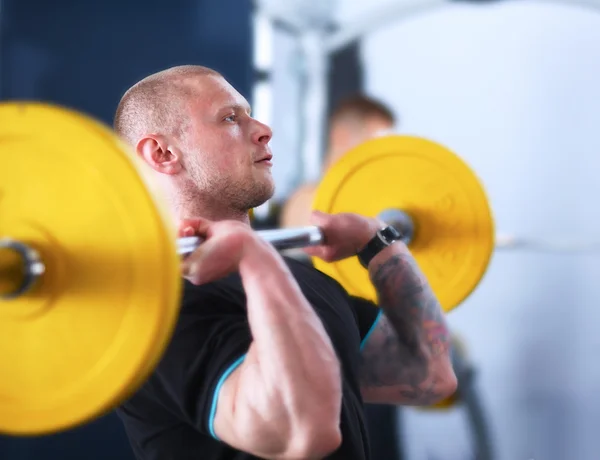 Shot of a young man performing bicep curls in a gym