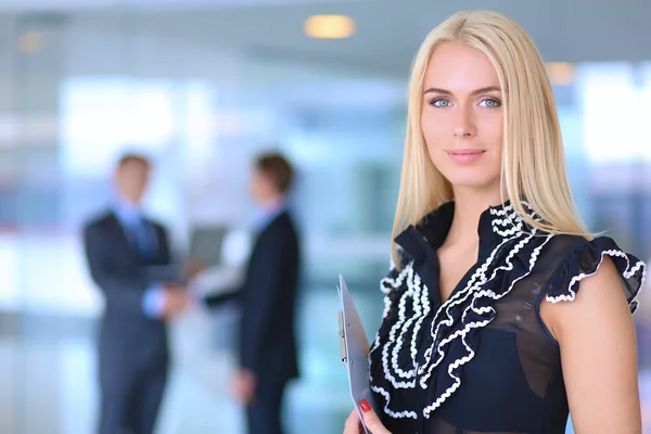 Portrait of a beautiful office worker standing in an office with colleagues in the background