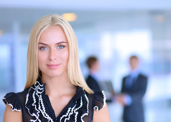 Portrait of a beautiful office worker standing in an office with colleagues in the background