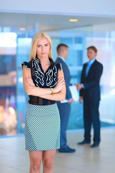 Portrait of a beautiful office worker standing in an office with colleagues in the background