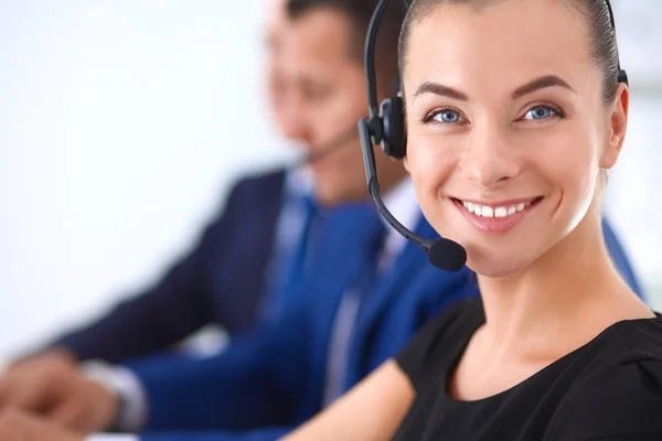 Portrait of beautiful business woman in headphones smiling with colleagues in background