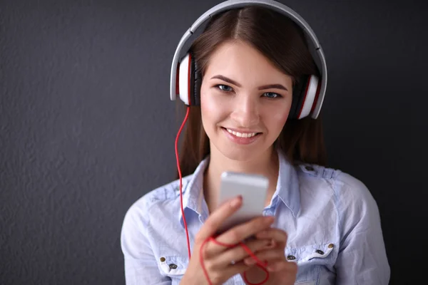 Smiling girl with headphones sitting on the floor near wall