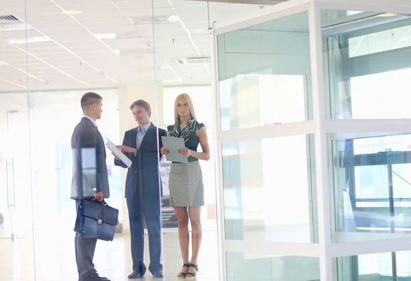 Business woman standing with her staff in background at modern office