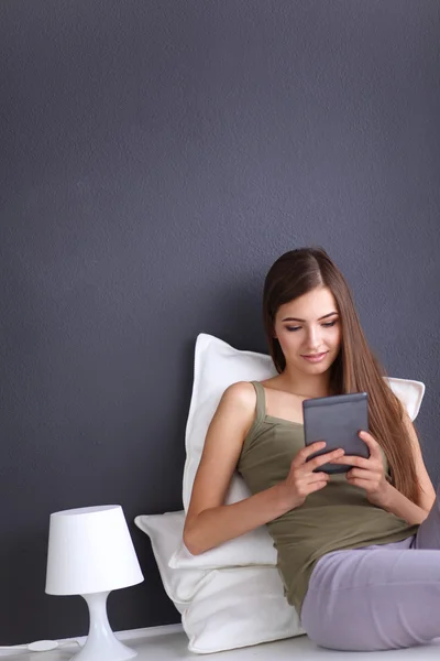 Pretty brunette woman sitting on the floor with a pillow and plane table