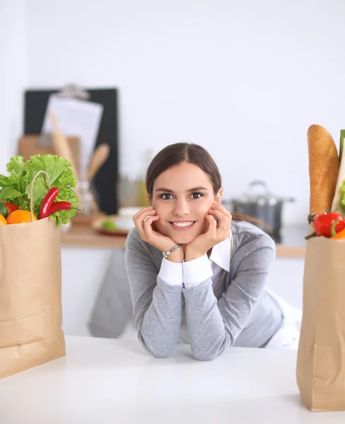 Beautiful young woman cooking looking at laptop screen with receipt in the kitchen