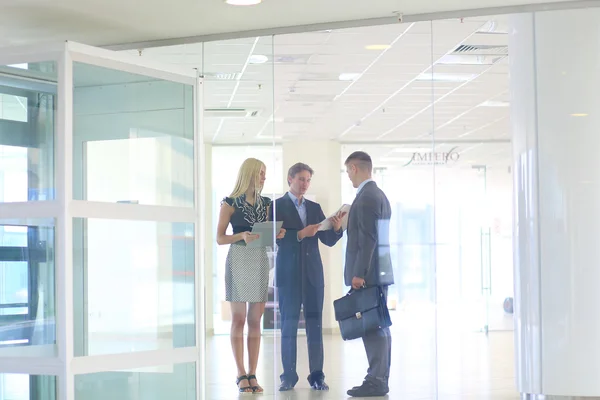 Business woman standing with her staff in background at modern office