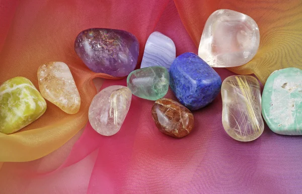 Close up of chakra gemstones on rainbow colored chiffon material