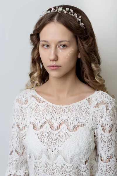 Young beautiful young girl with long curly hair, no makeup with a clean face with a wreath on his head portrait in the studio on a white background