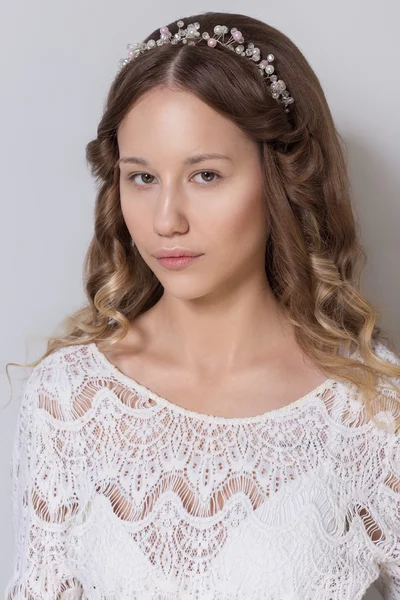 Young beautiful young girl with long curly hair, no makeup with a clean face with a wreath on his head portrait in the studio on a white background