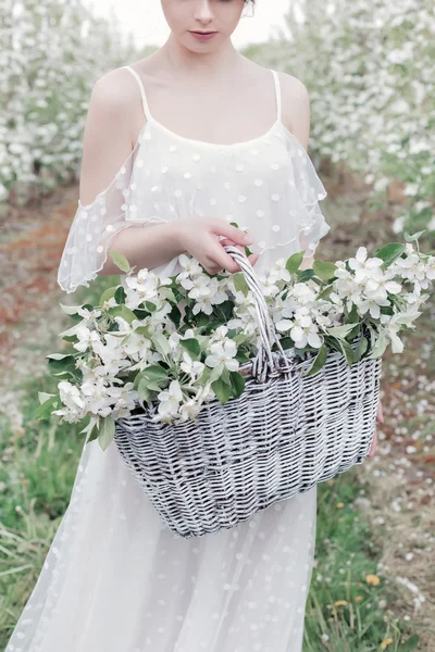 Beautiful sweet gentle happy girl in a beige boudoir dress with flowers in a basket holding, photo processing in the style of modern fine art