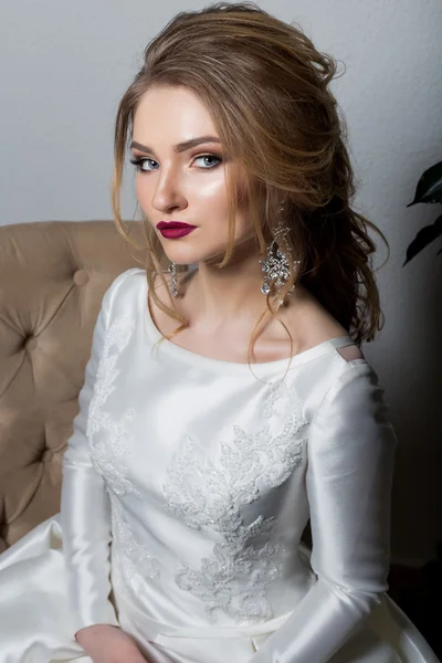 Portrait of a beautiful sexy cute girl happy bride in an elegant dress with bright makeup in a white dress with a gorgeous wedding hairstyle