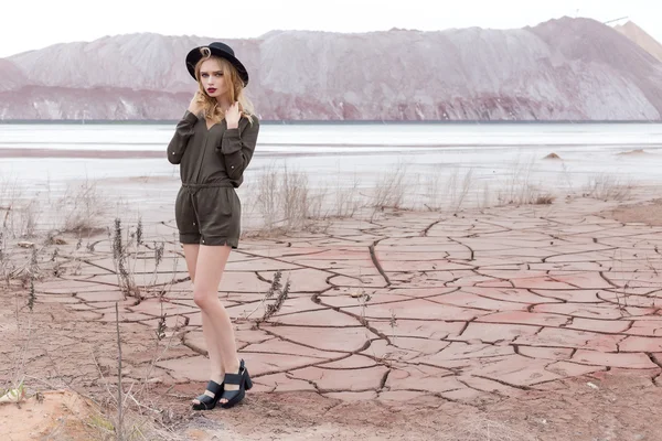 Fashion shot of a beautiful sexy girl in a black hat is removed in the desert for the magazine