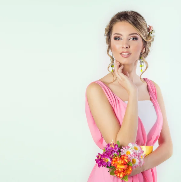 Delicate image of a beautiful woman girl like a bride with bright makeup hairstyle with flowers roses in the head in a long pink dress with flowers in hand
