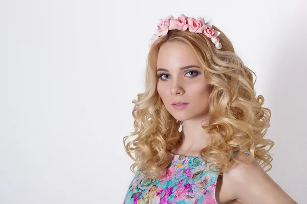 Fashionable portrait shot of a beautiful sexy girl in a cute blonde with curly hair wearing a wreath of flowers handmade in the evening image on a white background in studio
