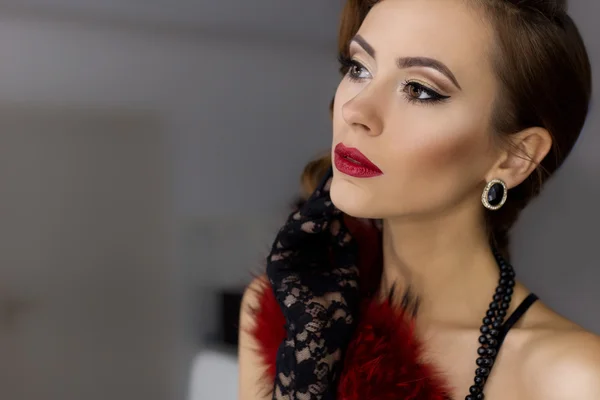 Beautiful sexy young woman flaunts front of the mirror in the dressing room in lacy underwear in a retro style with bright make-up and beautiful evening hairstyles , shot in the style of the 20s