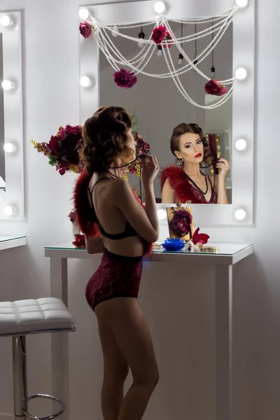 Beautiful sexy girl in lacy underwear rtro stands before the mirror in the dressing room is painted with beautiful bright evening make-up with stylish hairstyle retro style 20s , burlesque photo