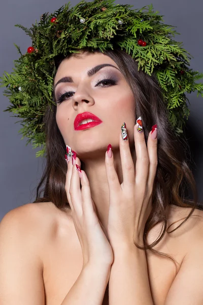 Christmas elegant fashion woman. Xmas New Year hairstyle and makeup. Gorgeous Vogue style Lady with Christmas decorations on her head, baubles, professional makeup, red lipstick long red evening dress
