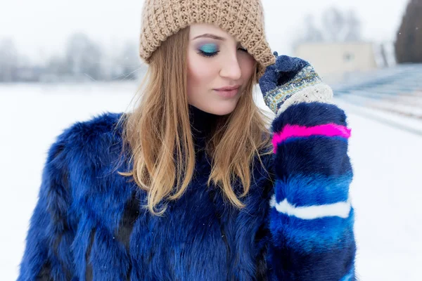 Beauty Fashion model girl in a fur coat Beautiful brunette woman with bright makeup in bright winter day