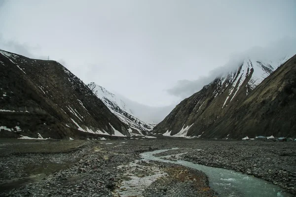 River in mountains under cloudy sky