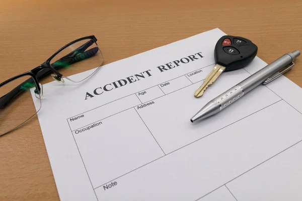 Accident report form with pen with glasses and key
