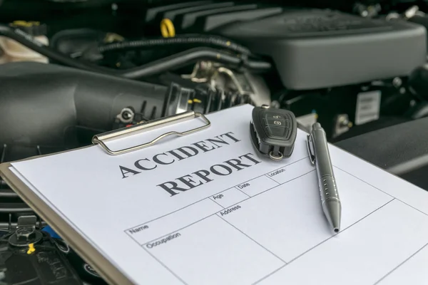 Mechanic Inspecting damage car and filling in accident report fo