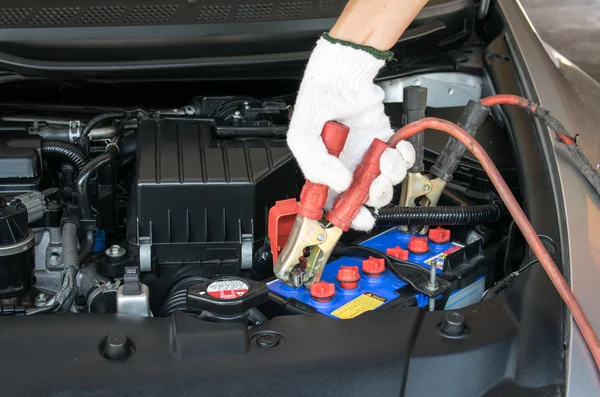 Automotive technician charging vehicle battery