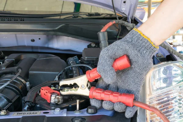 Automotive technician charging vehicle battery