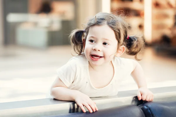 Closeup portrait of cute adorable smiling white Caucasian toddler girl child with dark brown eyes and curly pig-tails hair in white light dress tshirt looking in camera, copyspace for text
