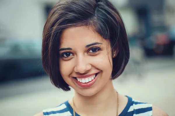Closeup portrait of beautiful smiling young latin hispanic girl woman with short dark black hair bob, black eyes, outside looking in camera, toned with Instagram filters, natural smile emotion
