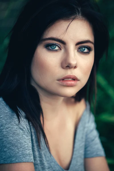 Closeup portrait of beautiful pensive sad young Caucasian girl woman with black hair, blue eyes, looking in camera, toned with Instagram filters, natural beauty youth look