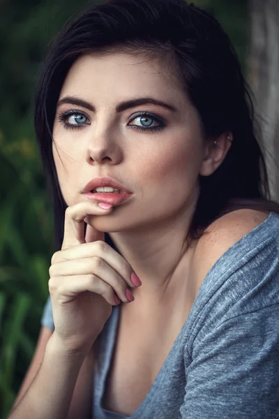 Closeup portrait of pensive thoughtful sexy beautiful young Caucasian woman with black hair, blue eyes, looking in camera, toned with filters, natural beauty youth look