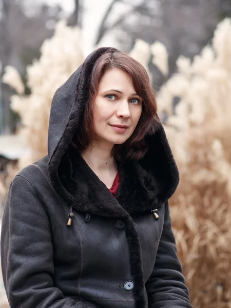 Closeup portrait of beautiful middle age white caucasian brunette woman with green eyes in coat jacket on fall autumn day outside looking in camera on yellow rye background