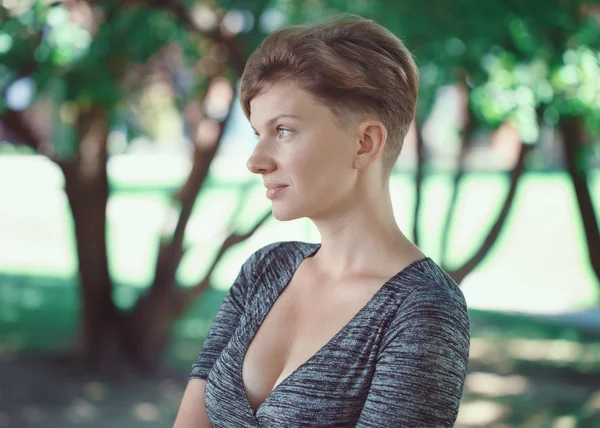Portrait of smiling young middle aged white caucasian girl woman with short hair stylish haircut  in tshirt looking away outside in summer park, beauty fashion lifestyle