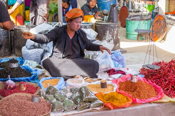 Woman in traditional dress sells vegetables at market of Inn Dain Khone Village, on Inle Lake.