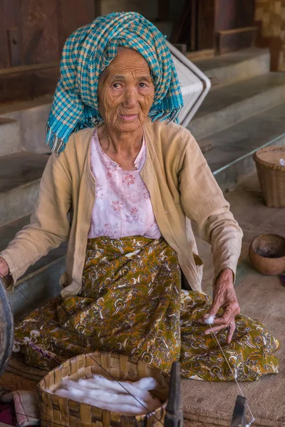 Elderly woman burnese produces cotton with traditional instruments in a village of Bagan